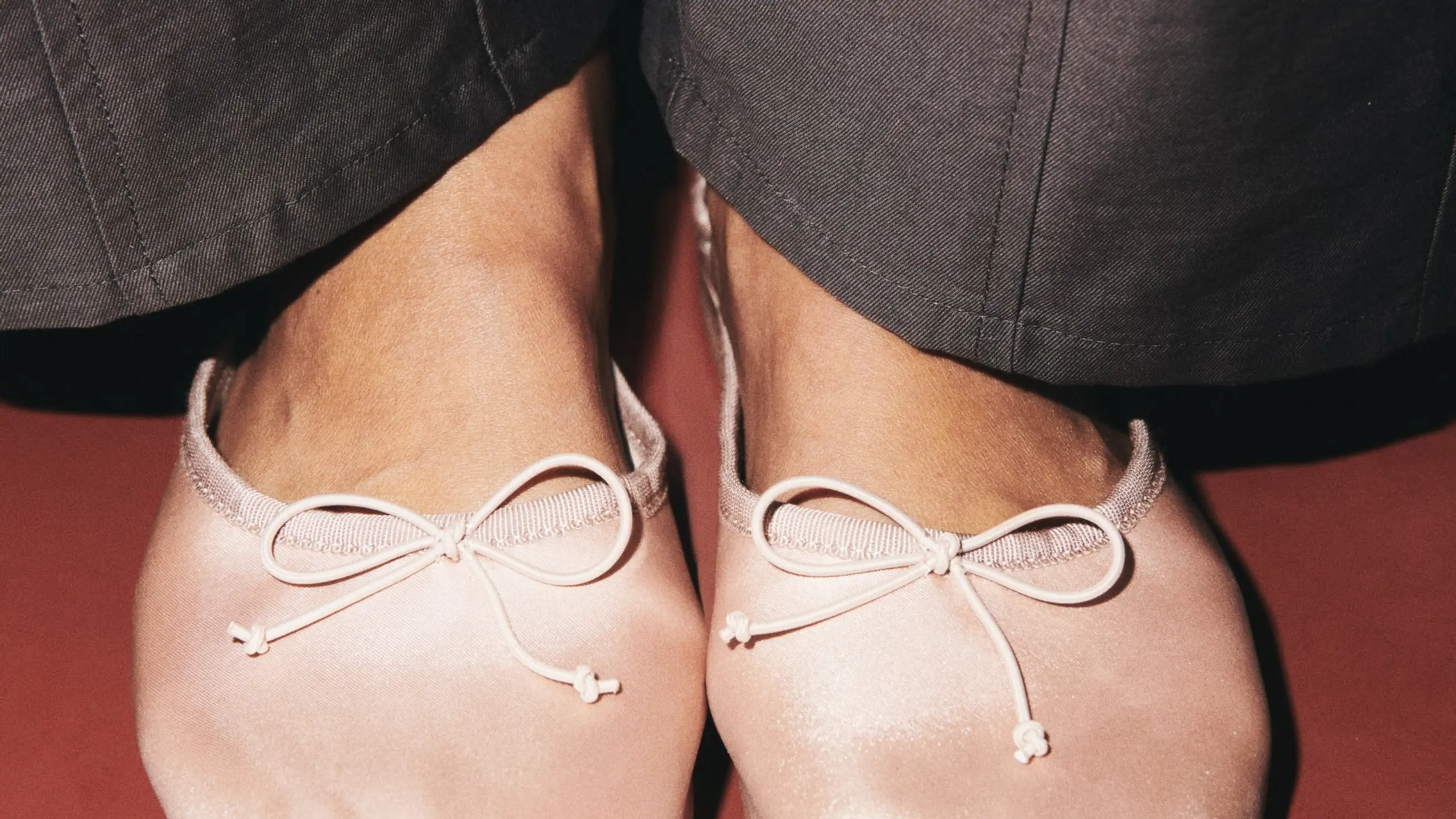 Close-up mit rosa Satin Ballerina mit Schleifen und grauer Anzughose