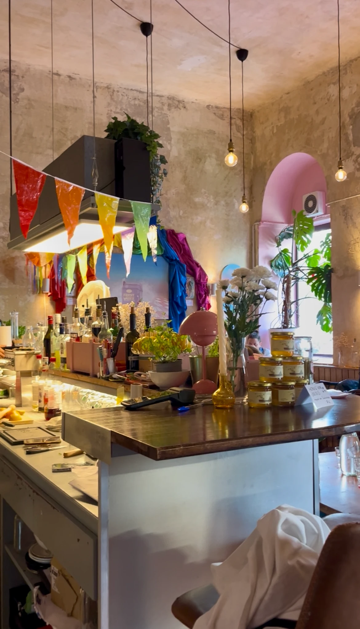 Gemütliche Bar- und Thekenlandschaft in einem Café mit bunten Wimpelketten, Hängeleuchten und Flaschen