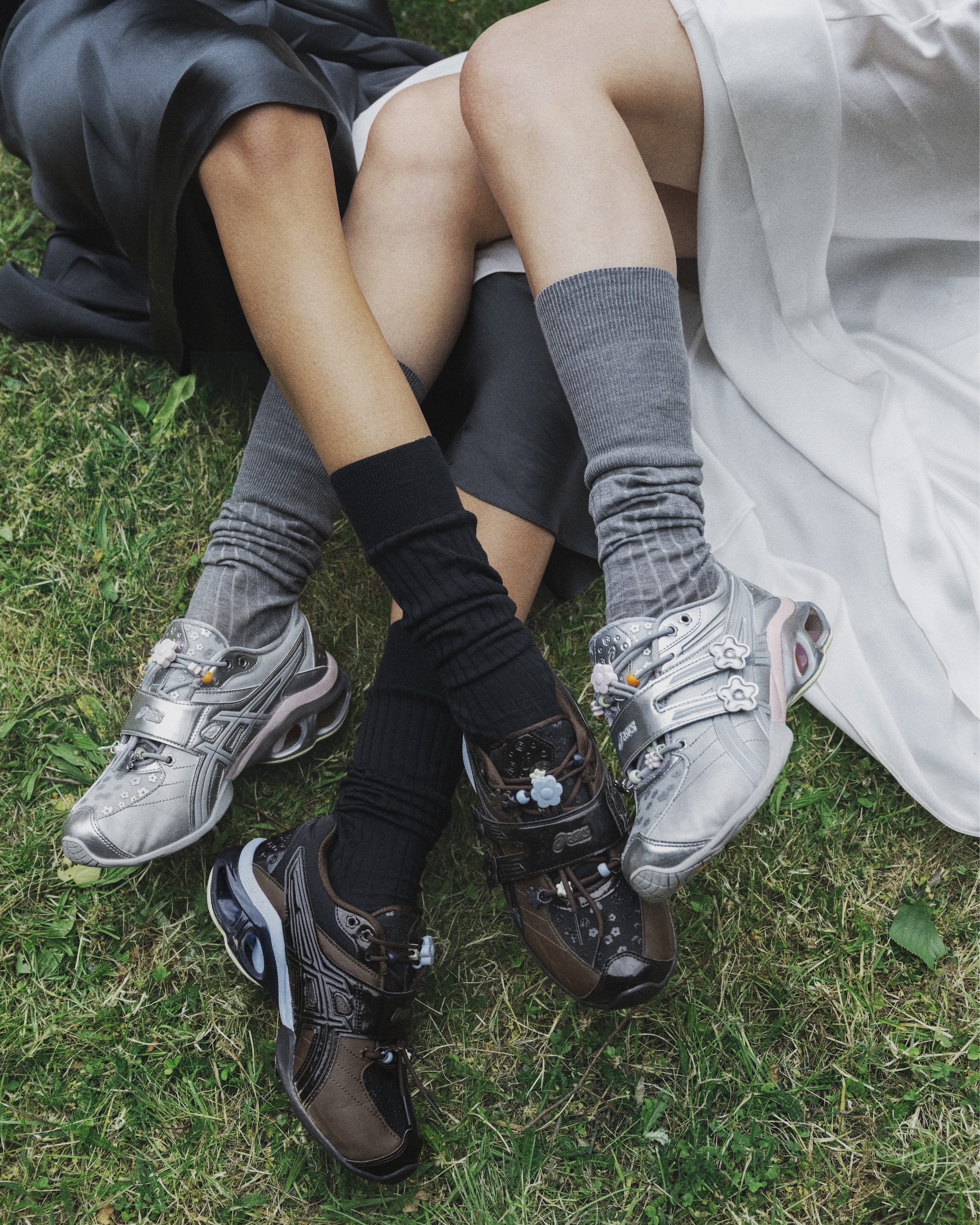 Close-up von zwei Frauen aus einer Wiese mit den Schuhen, hohen Tennissocken und langen Röcken