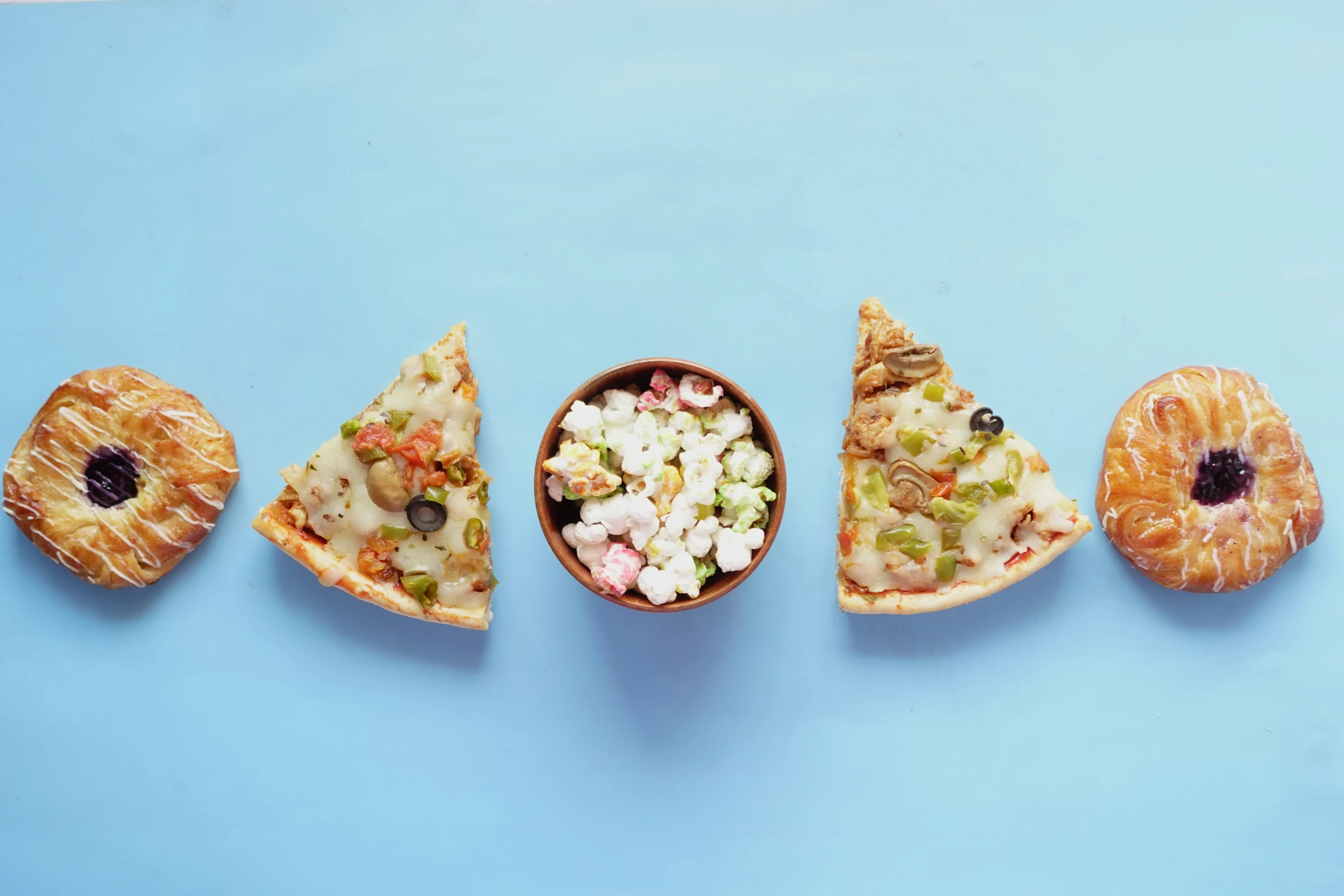 Ein Stück Pizza und eine Schüssel Popcorn auf blauem Hintergrund