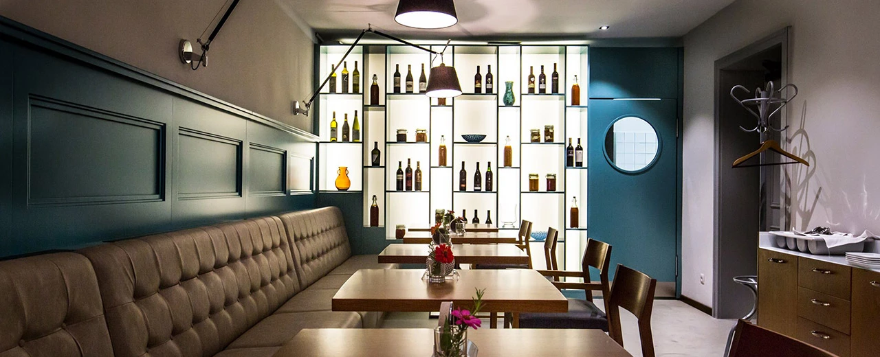 © MIR Stilvolles Restaurant-Interieur mit braunen Ledersitzen, Holztischen und einer beleuchteten Weinauswahl. Modernes Design mit Teal und Beige.