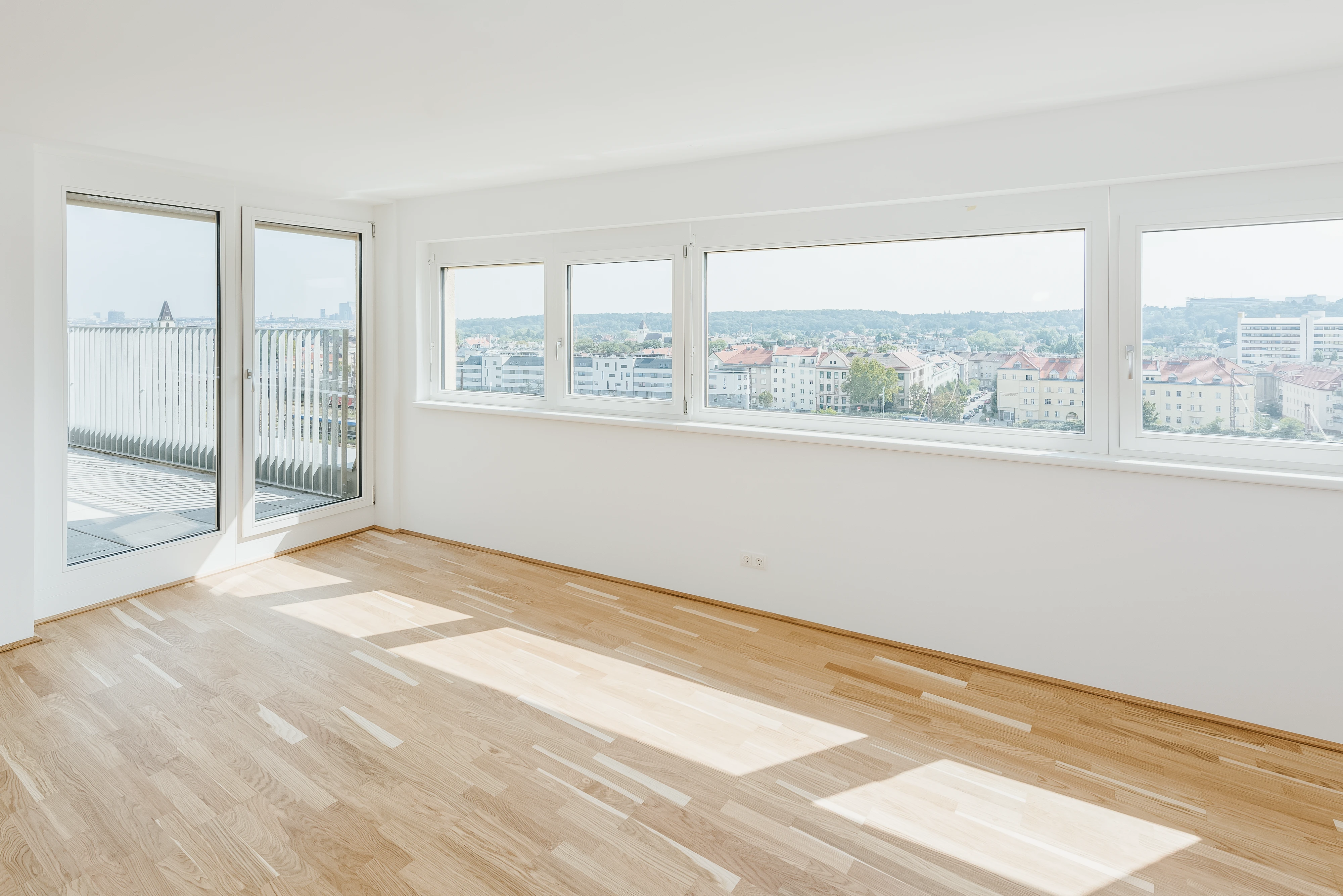 Blick aus Wohnzimmer auf Balkon und durch Fensterfront auf Stadt