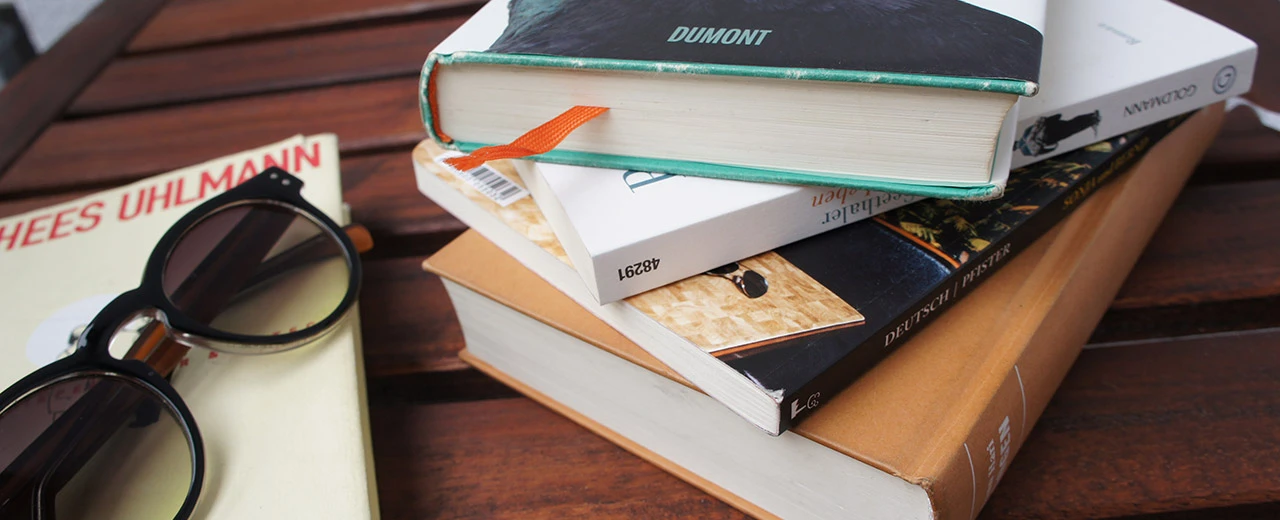 Bücherstapel mit Sonnenbrille auf Holztisch.  Bild erstellt mit NEX-5.