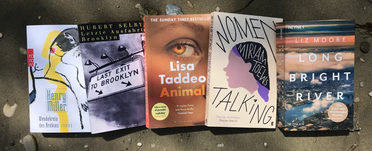 © Romina Fünf Bücher liegen im Sand: Henry Miller - Wendekreis des Krebses, Hubert Selby Jr. - Letzte Ausfahrt Brooklyn, Lisa Taddeo - Animal, Miriam Toews - Women Talking, Liz Moore - Long Bright River.