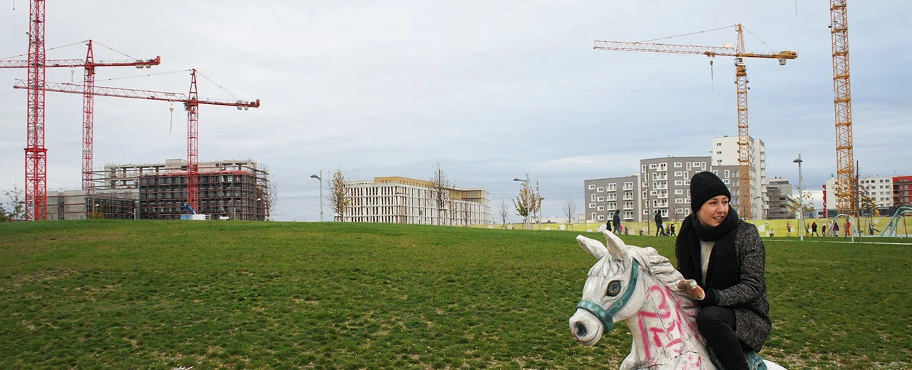 © Ingo Kummer Junge Frau auf einem Karussellpferd vor dem Hintergrund einer modernen Stadtlandschaft mit Baukränen. Erstellt mit NEX-5 v1.05