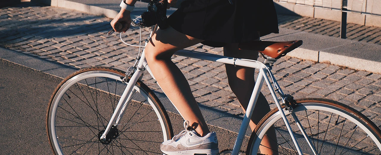 Frau fährt ein weißes Fahrrad auf einem gepflasterten Weg.  Bild erstellt mit Adobe Photoshop.