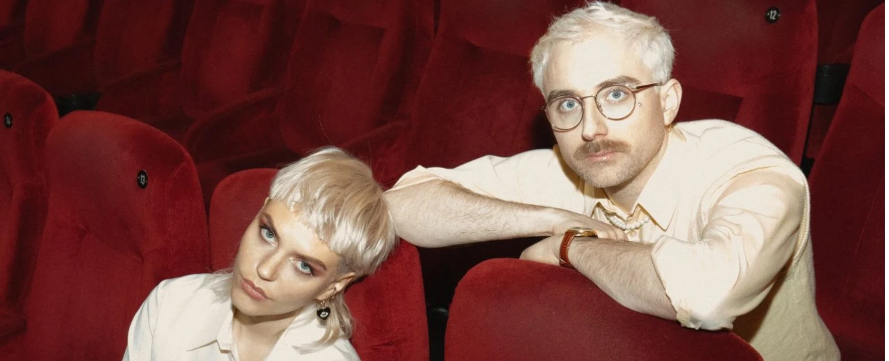 ©  Porträt von zwei Personen in einem roten Kinosaal. Konzertankündigung.