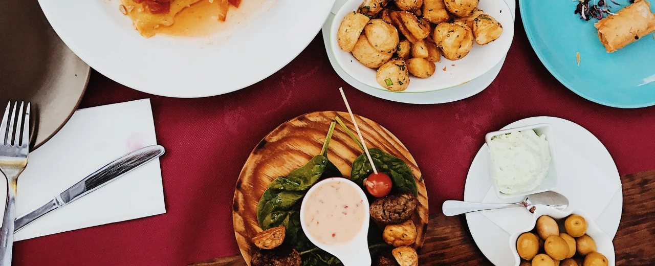 © Pexels Verschiedene Tapas: gebratene Kartoffeln, Fleischbällchen, Dip, Oliven & Spinat.