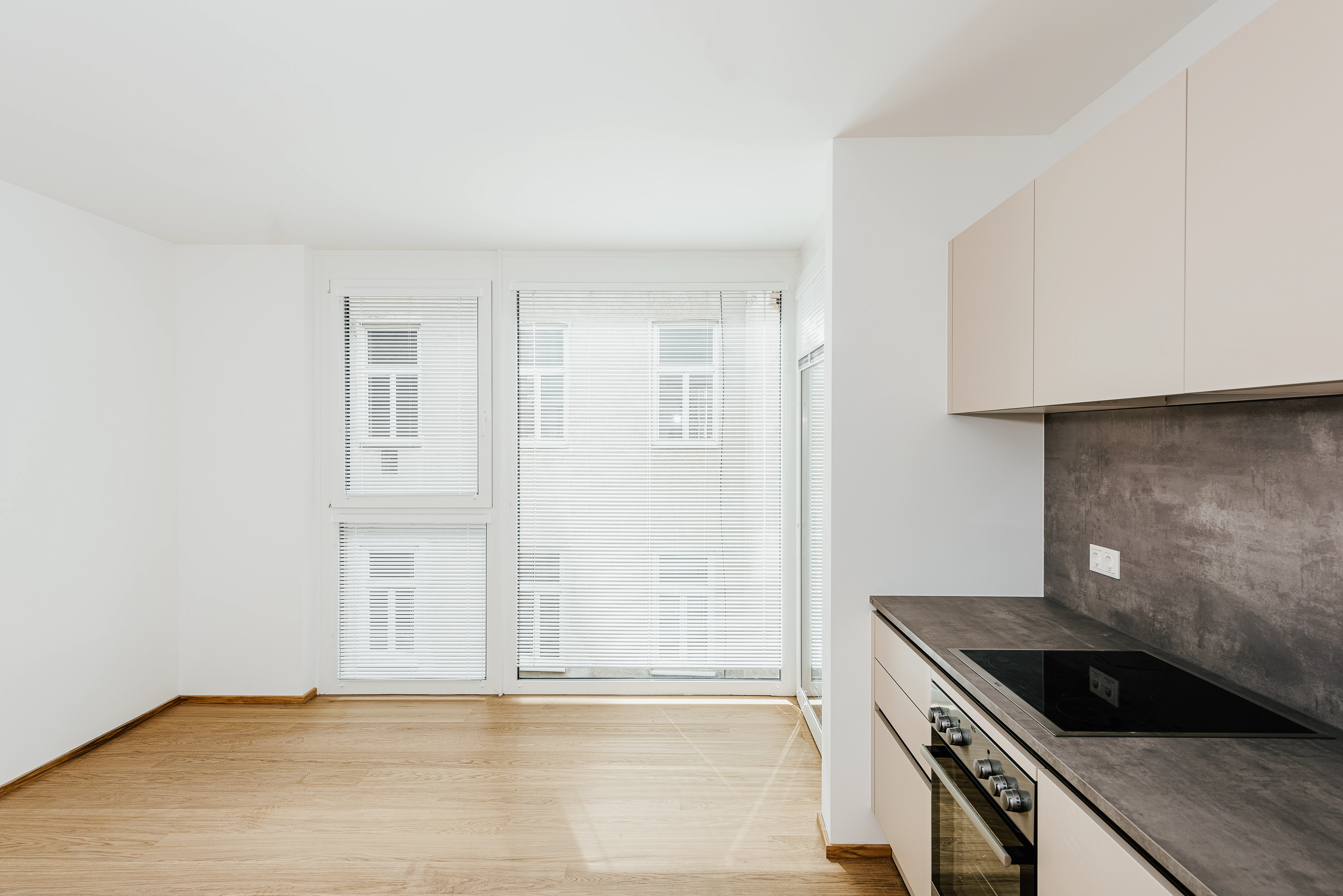 Moderne Küche mit dunkelgrauer Arbeitsplatte und Fenstern mit Jalousien