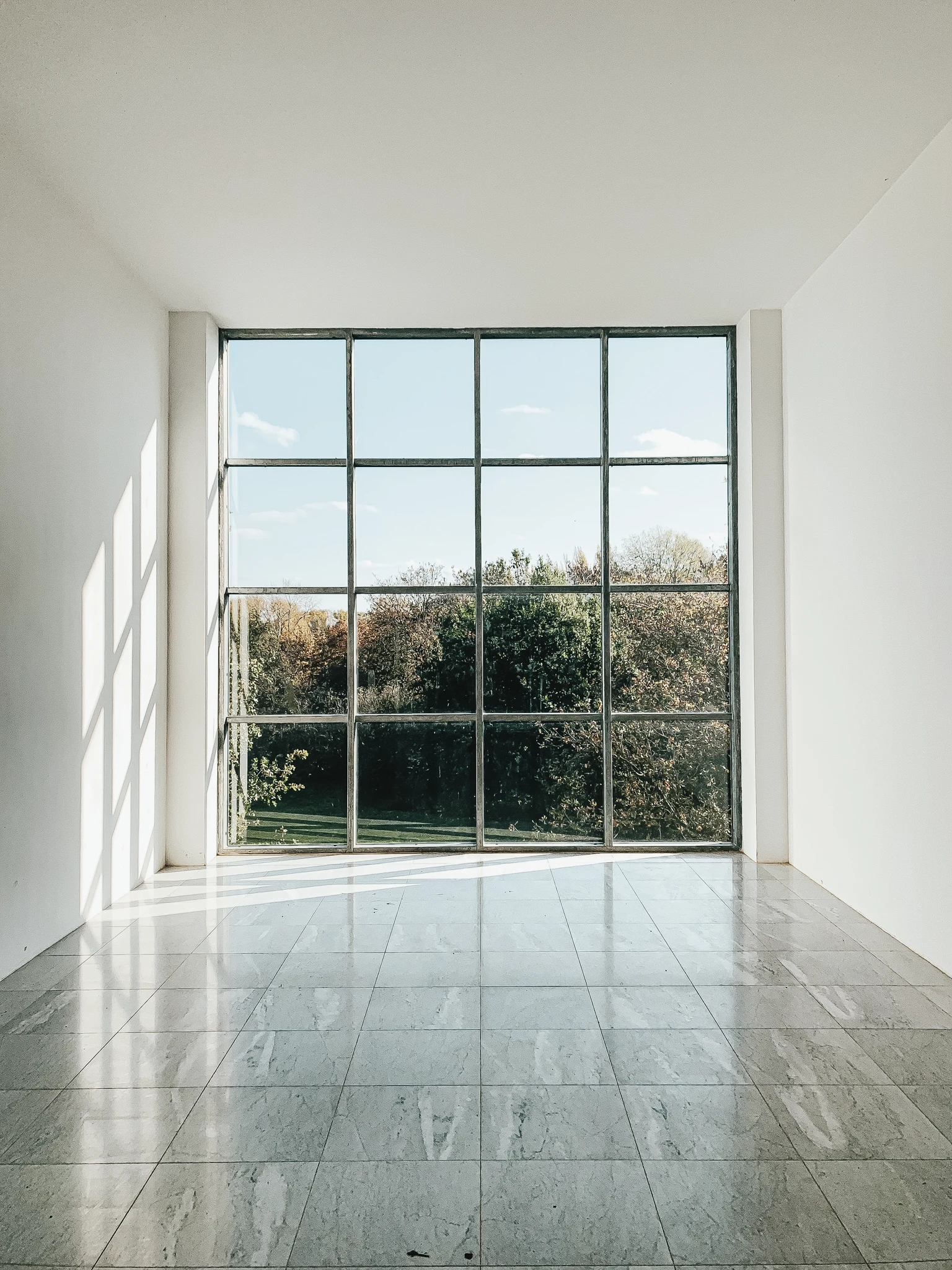 Blick durch wandhohes Gangfenster mit quadratischen Glaspanelen