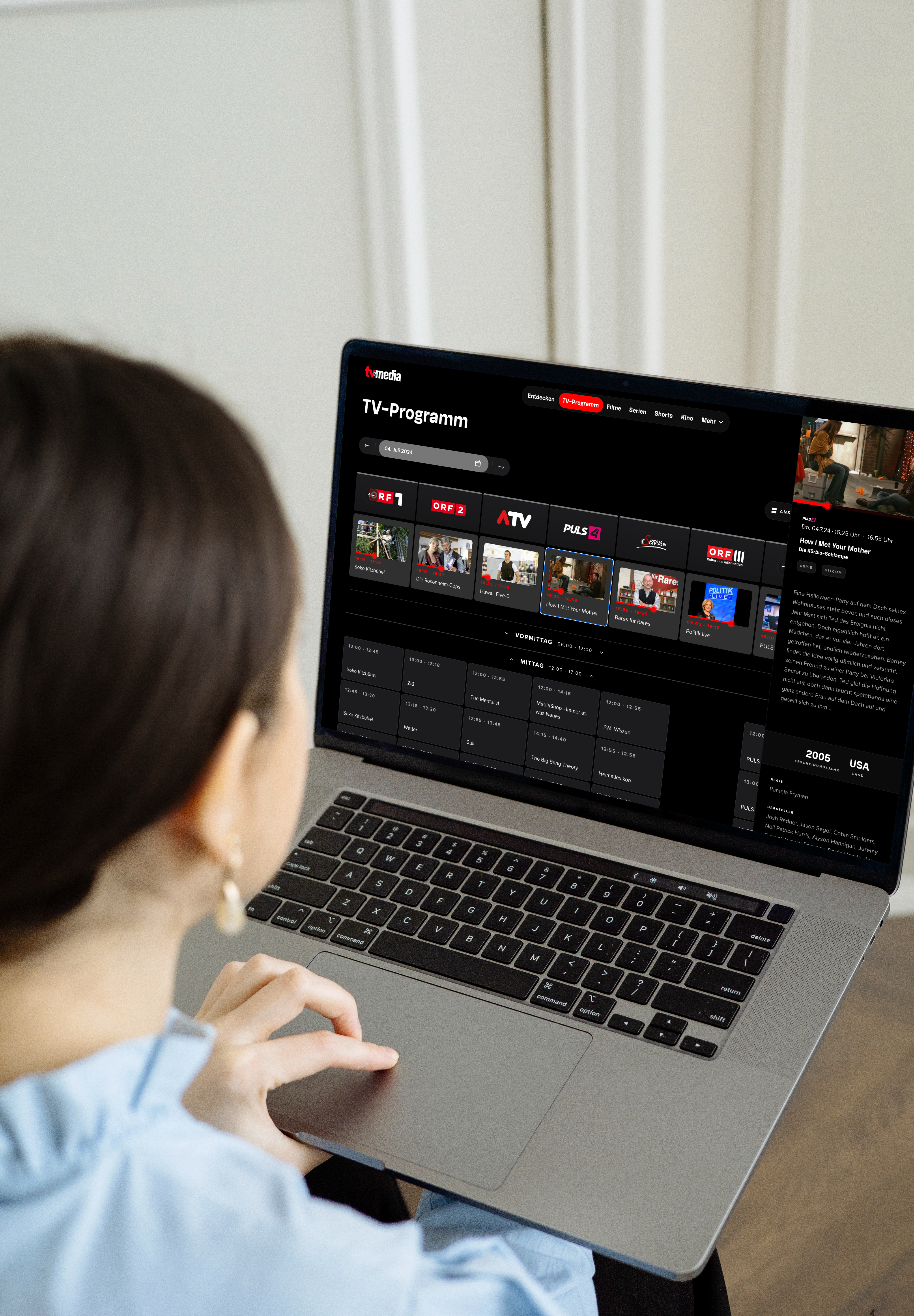 A woman using a laptop to browse a TV guide website called tvmedia.