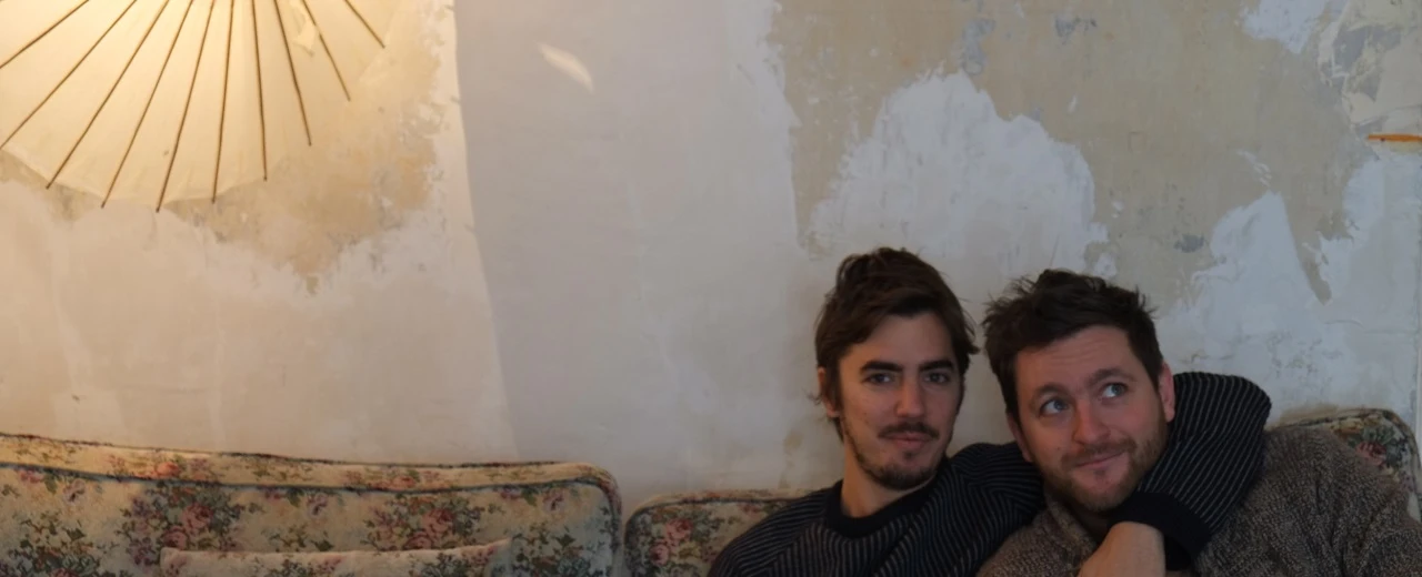 Zwei Männer entspannen auf einem Sofa vor einer alten Wand. Freundschaftsbild, Lifestyle.