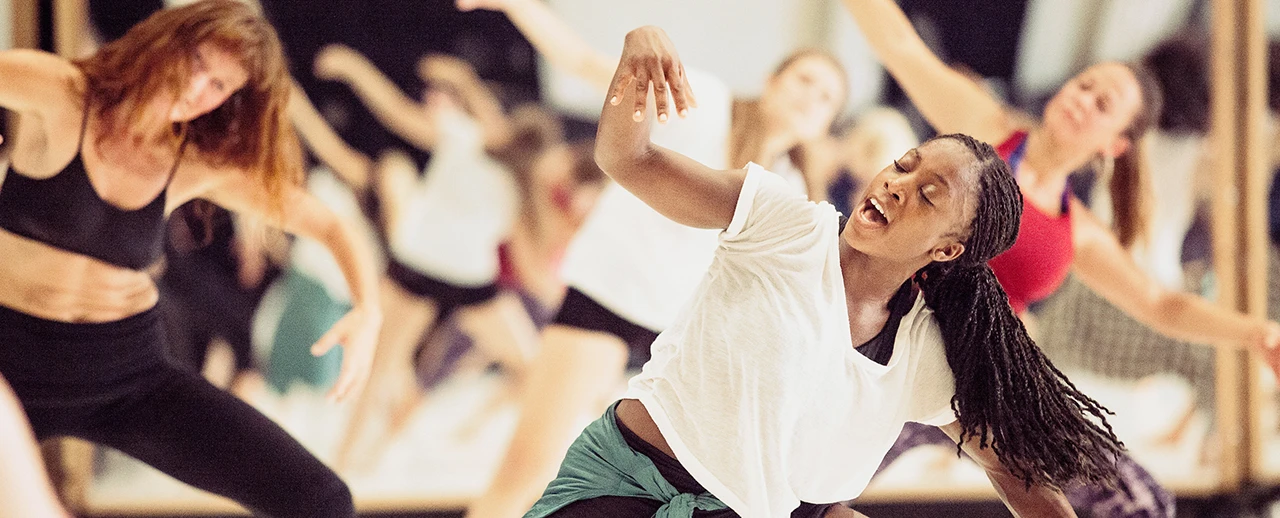 Leidenschaftlicher Tanz: Junge Tänzerin im Mittelpunkt, andere Tänzer im Hintergrund unscharf. Moderne Tanzperformance.