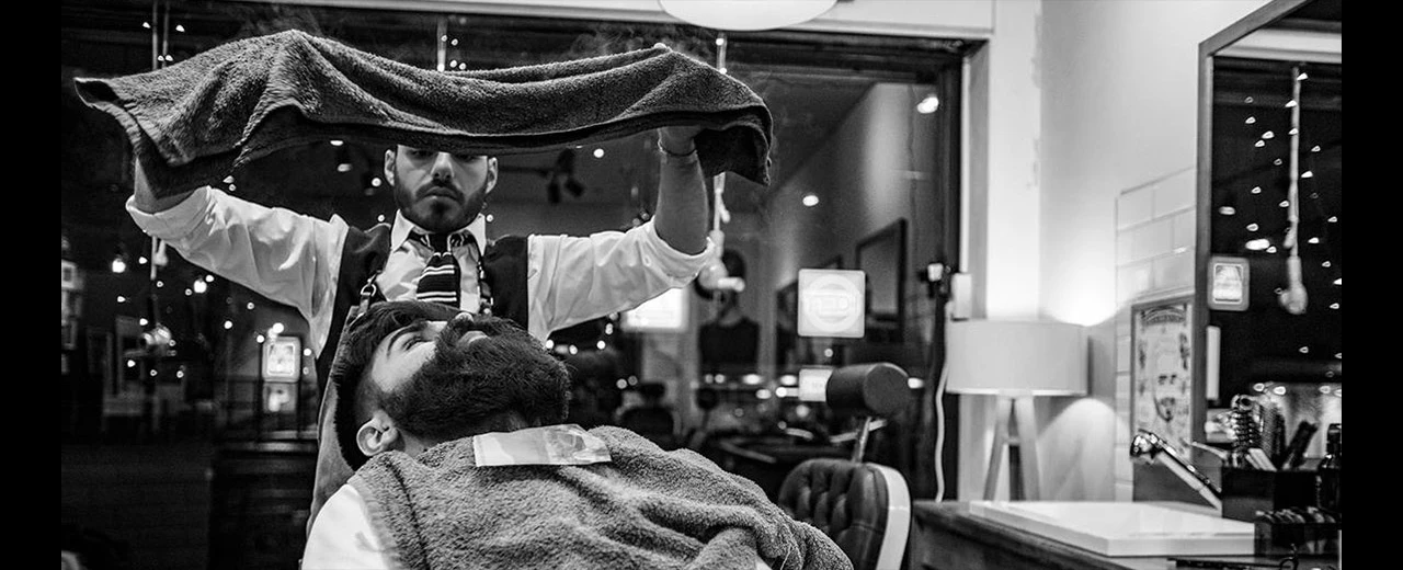 Barbier wäscht Kunden die Haare in einem modernen Barbershop. Schwarz-Weiß Foto.