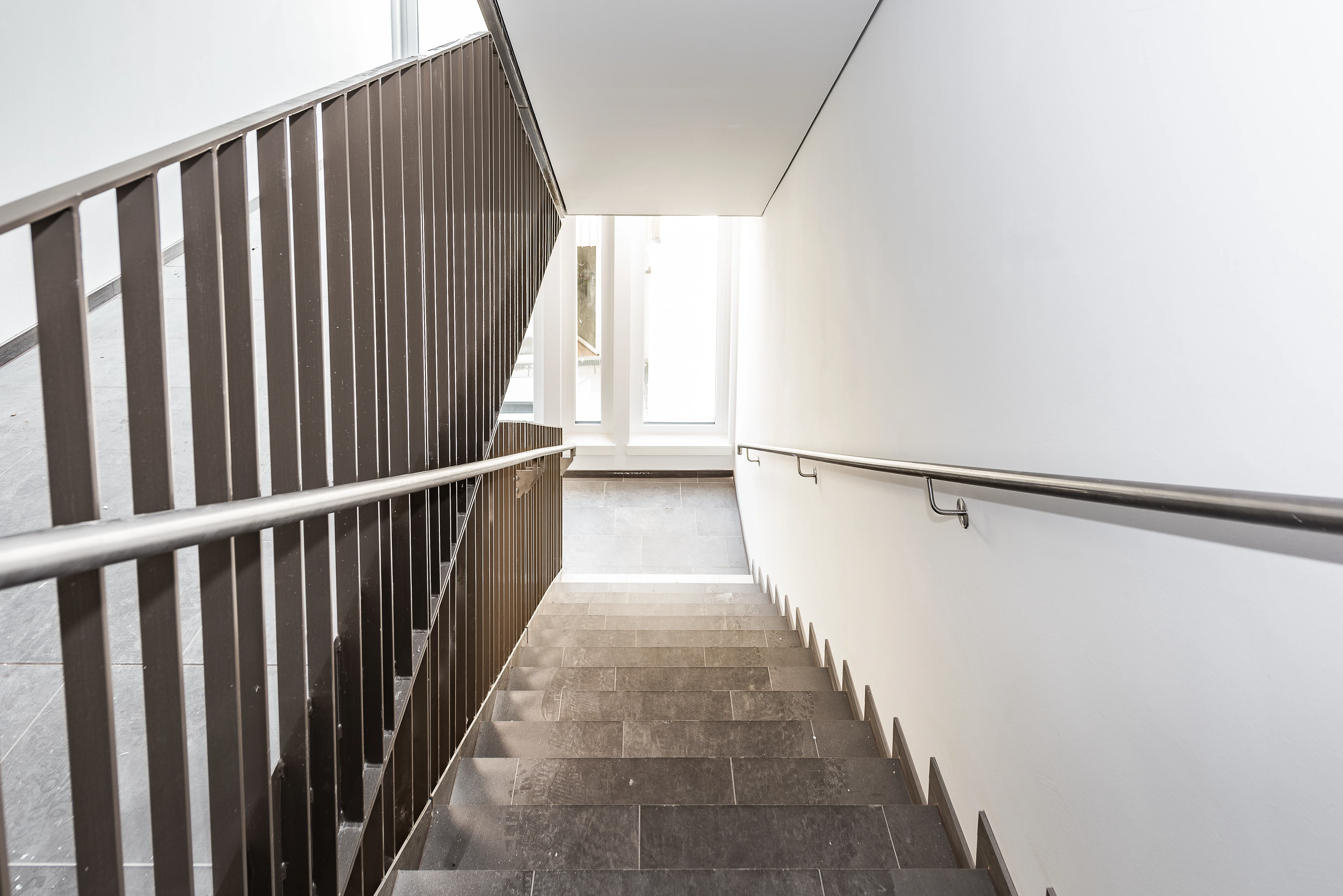 Stiegenhaus aus dunklen Platten und silbernem Geländer