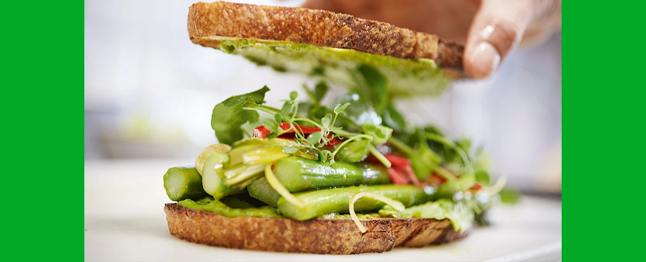 Appetitliches vegetarisches Sandwich mit Spargel, Kräutern und Pesto auf knusprigem Brot.