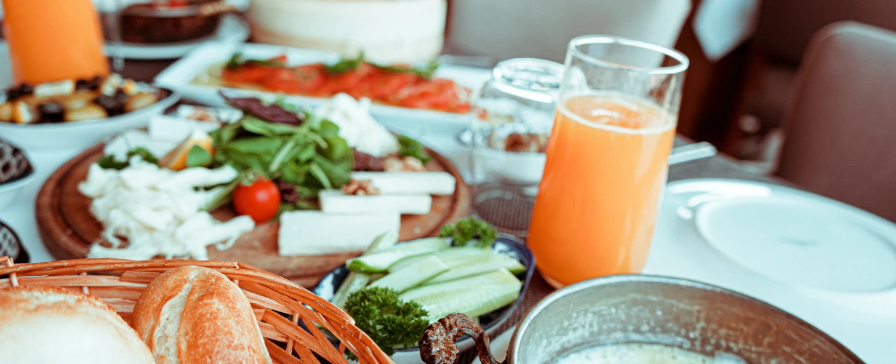 Leckeres Brunch-Buffet mit Käse, Gemüse, Brot und Orangensaft.