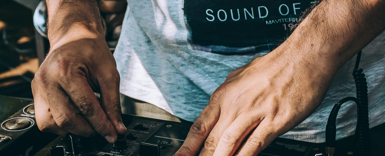 Nahaufnahme der Hände eines DJs an einem Mixer. Perfekte Illustration für Musikproduktion, DJing und elektronische Musik.