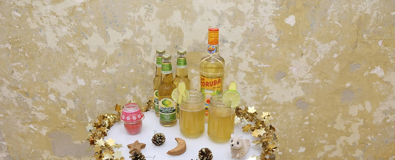 Festlicher Apfelwein-Cocktail in Gläsern mit weihnachtlicher Deko. Somersby & Rum im Hintergrund.