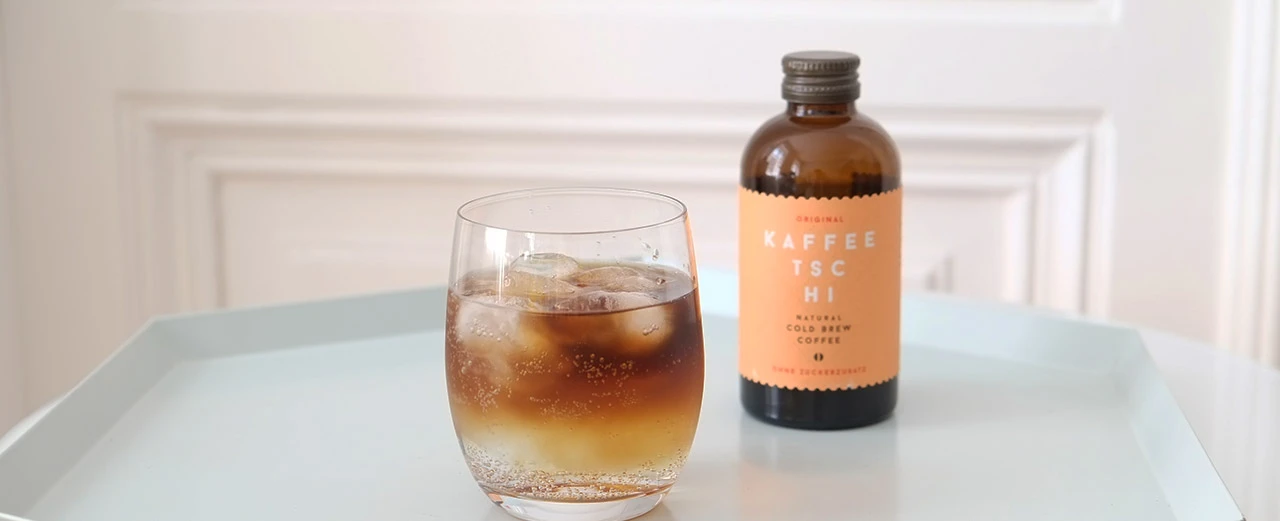 Glas kalter Brühkaffee mit Eis, neben Flasche Kaffee TSC HI. Zuckerfrei.