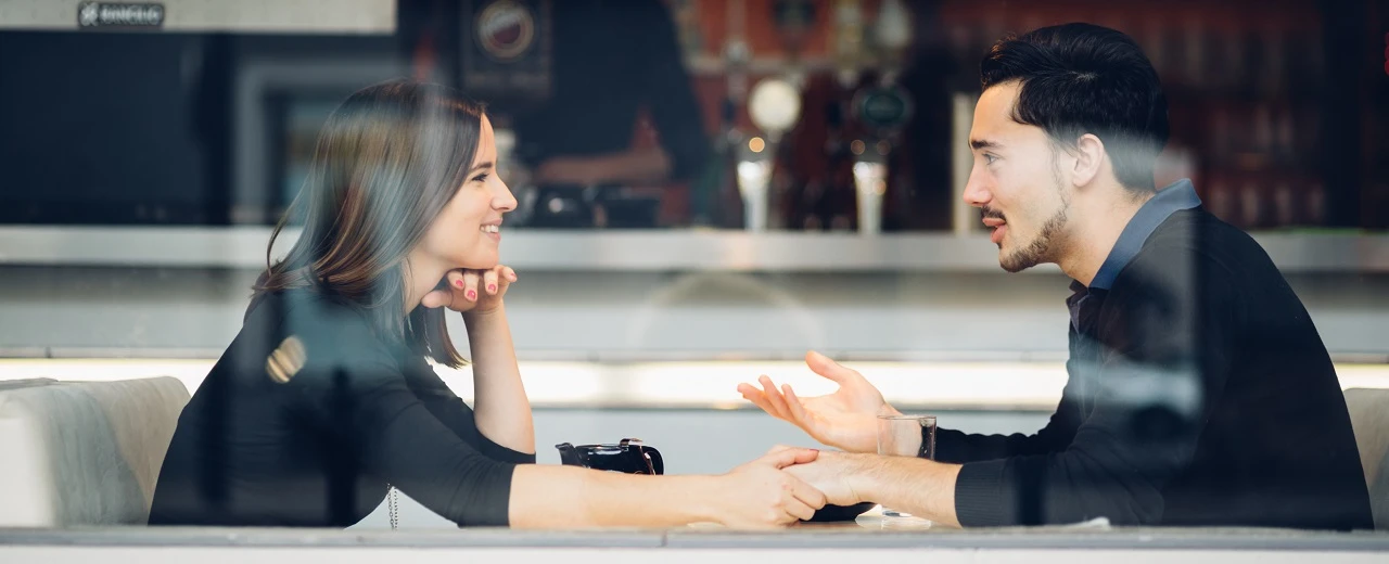 Liebespaar im Café, Händchen haltend und sich unterhaltend. Intimes Treffen in gemütlicher Atmosphäre.