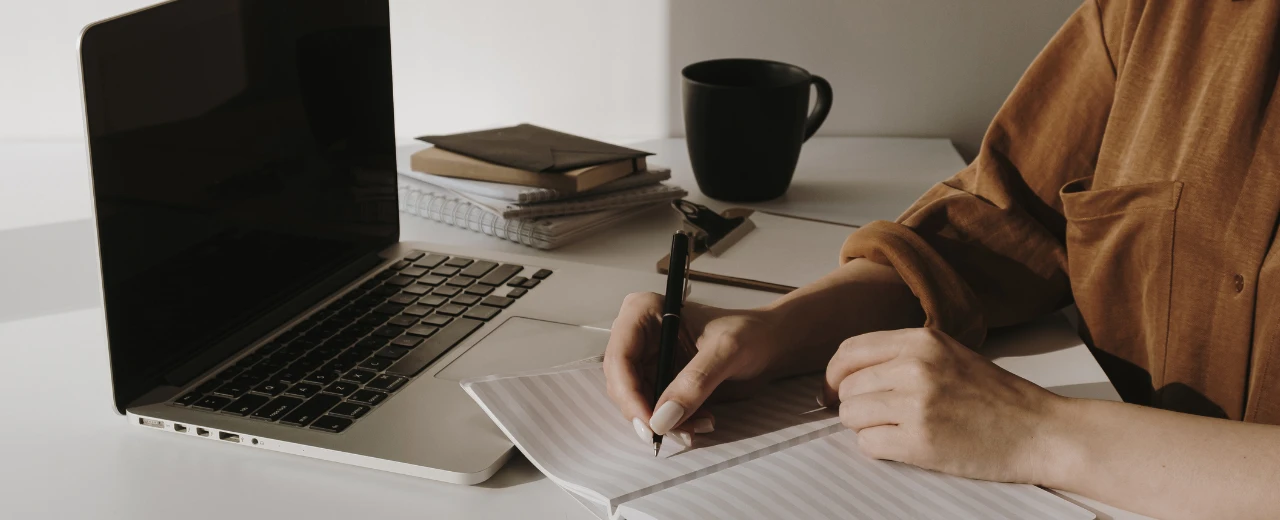Person schreibt Notizen am Laptop.  Produktivität am Arbeitsplatz. Homeoffice.
