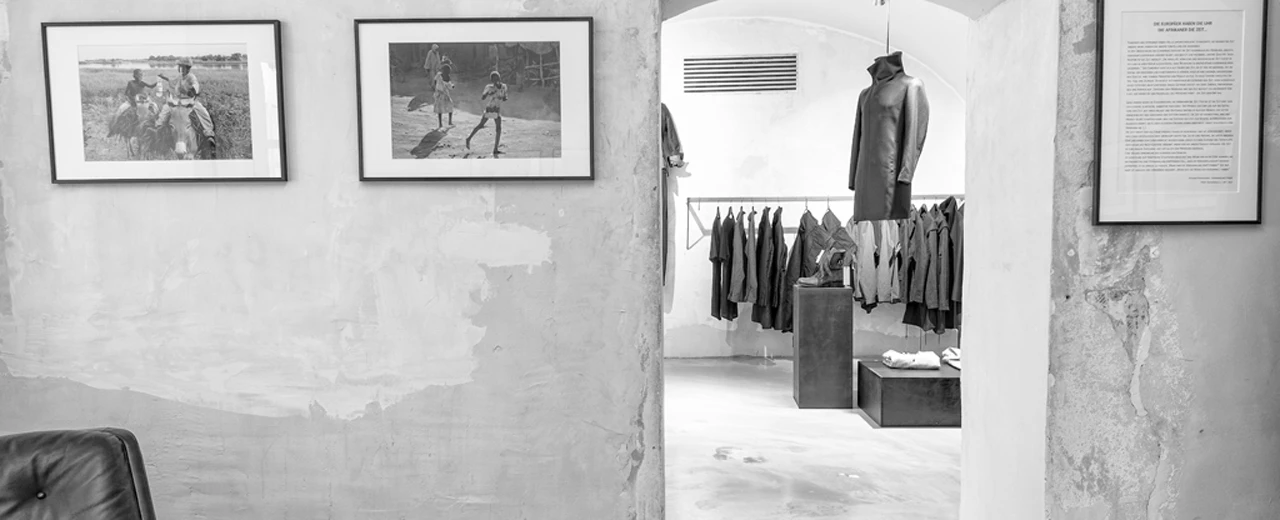 Schwarz-weiß Foto eines minimalistischen Ladens mit Kleidung, gerahmten Fotos und Betonwänden. Copyright © Toni Tramezzini.