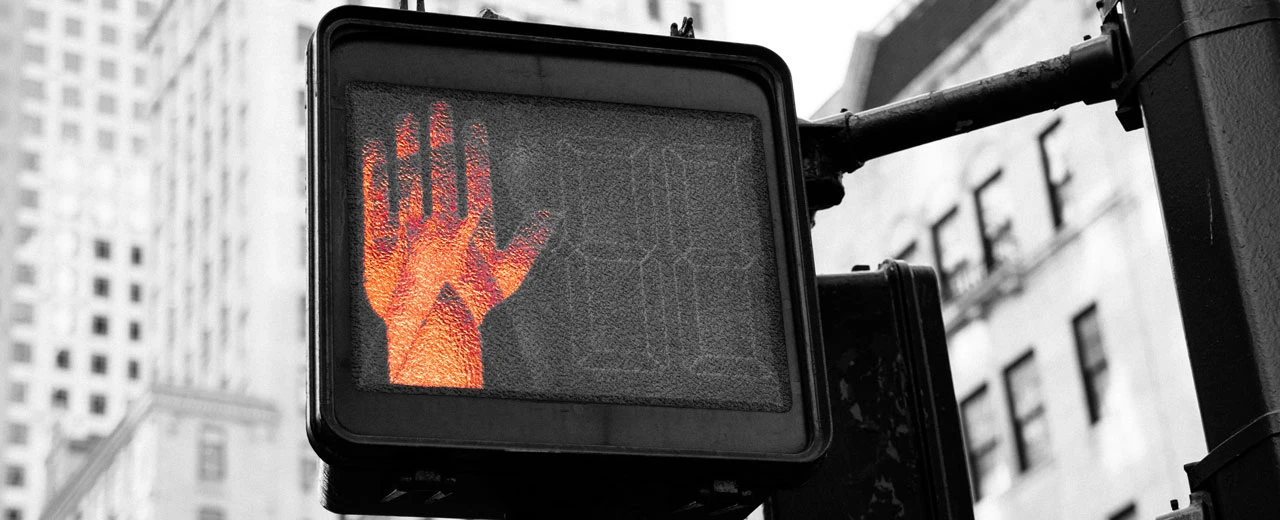 Nahaufnahme einer Fußgängerampel mit roter Hand (Halt). Schwarz-weiß Foto, orange Hand.
