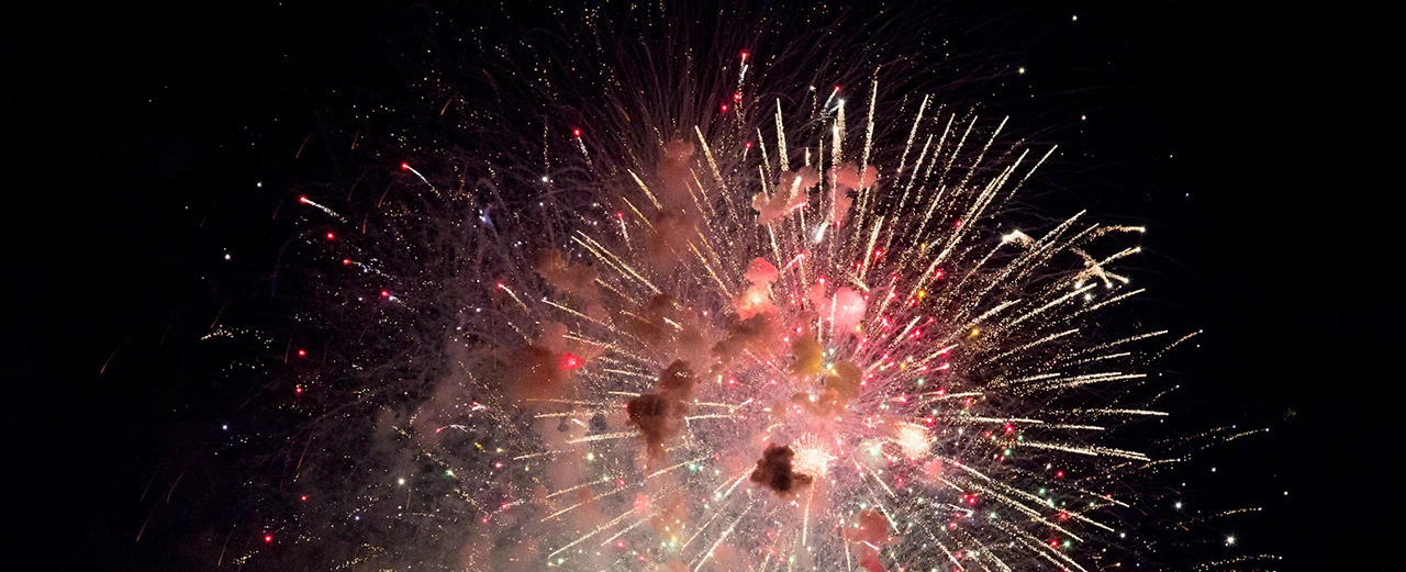 Atemberaubendes Feuerwerk am Nachthimmel mit roten, weißen und goldenen Funken.