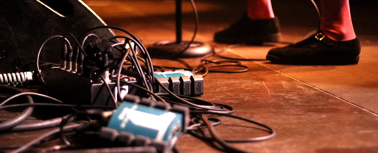 © Andrea Putz Kabelgewirr auf der Bühne nach einem Konzert. XLR-Kabel, Audio-Interfaces und Pedalboards liegen durcheinander.