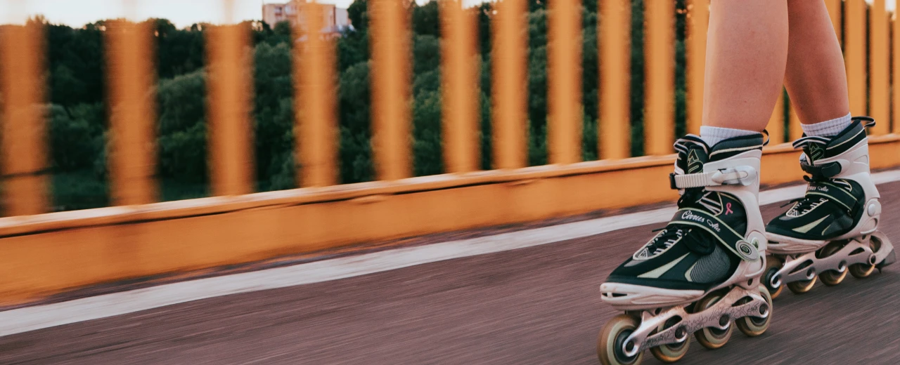 © unsplash Person fährt Inline-Skates auf einer Straße mit orangener Brüstung.  Geschwindigkeit, Bewegung, Outdoor-Aktivität.